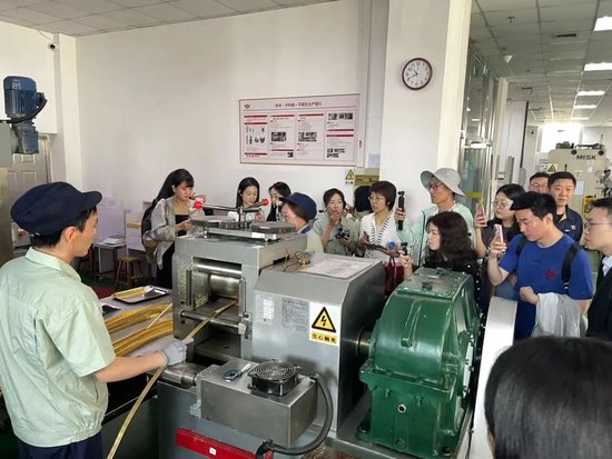 招金精炼讲解员为媒体参访团介绍开料、压片等工艺流程